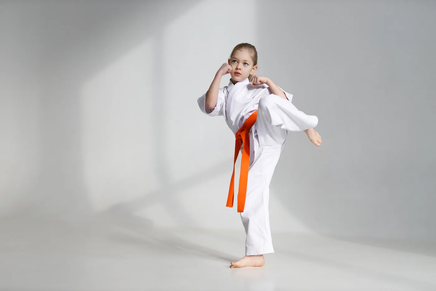Clase de artes marciales: niña de karate en patada lateral